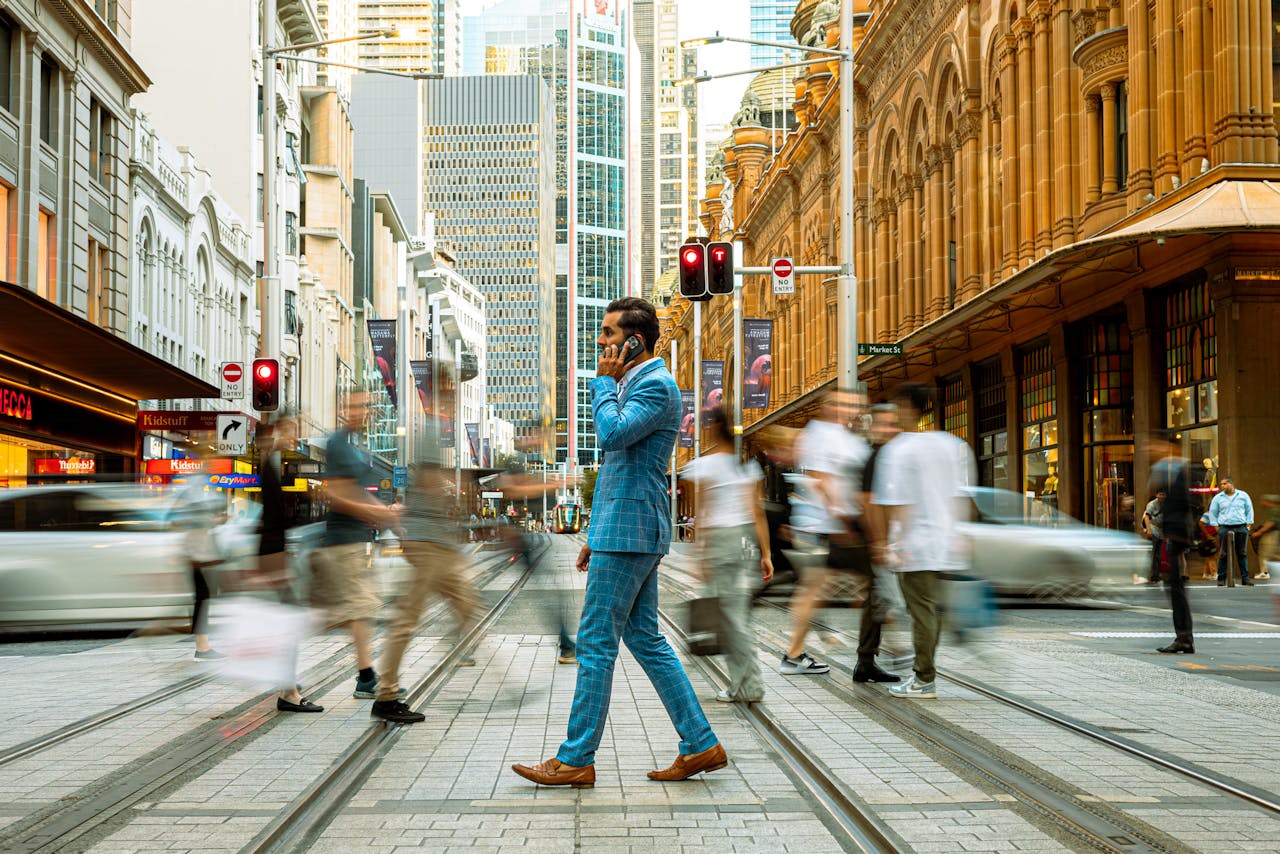 Services A businessman in a blue suit crosses a busy street in Sydney, Australia, surrounded by motion-blurred pedestrians.
