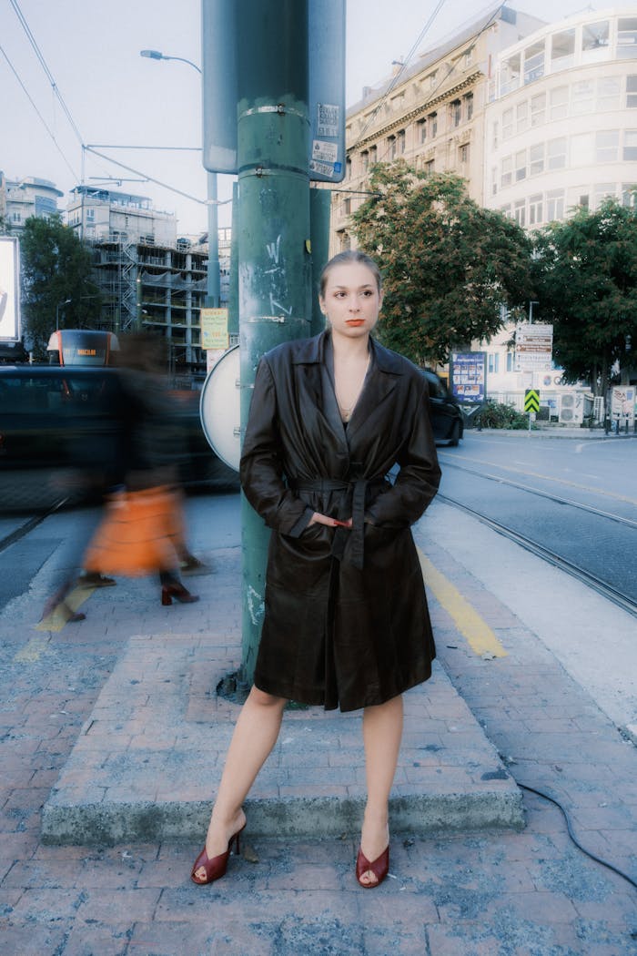 The Art of Drawing Readers In: Your attractive post title goes here Stylish woman in coat poses confidently in urban city setting, blurring motion around her.